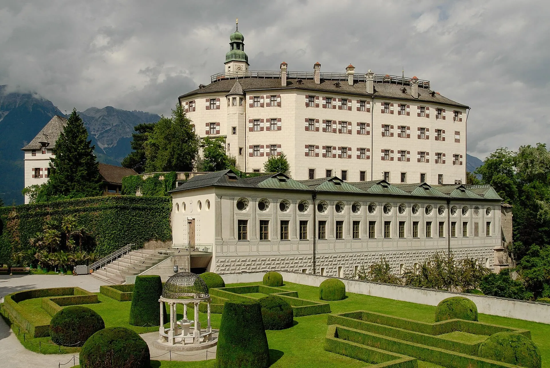 Ambras Castle above its formal gardens, with snow on the mountains behind