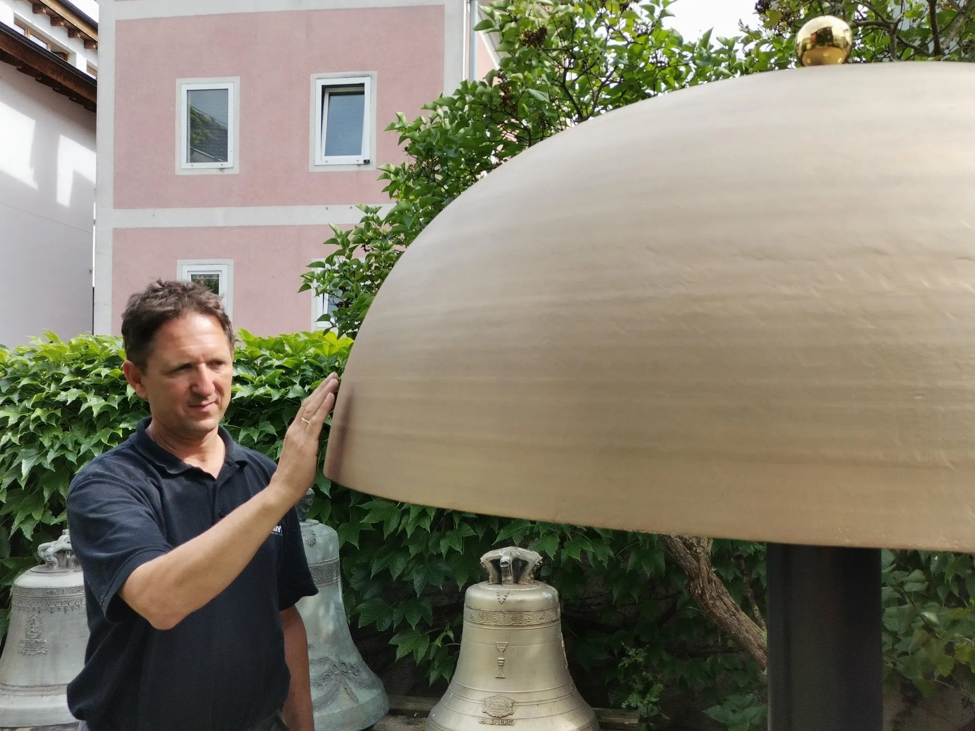 Bell founder touching a large bell in the Grassmayr garden