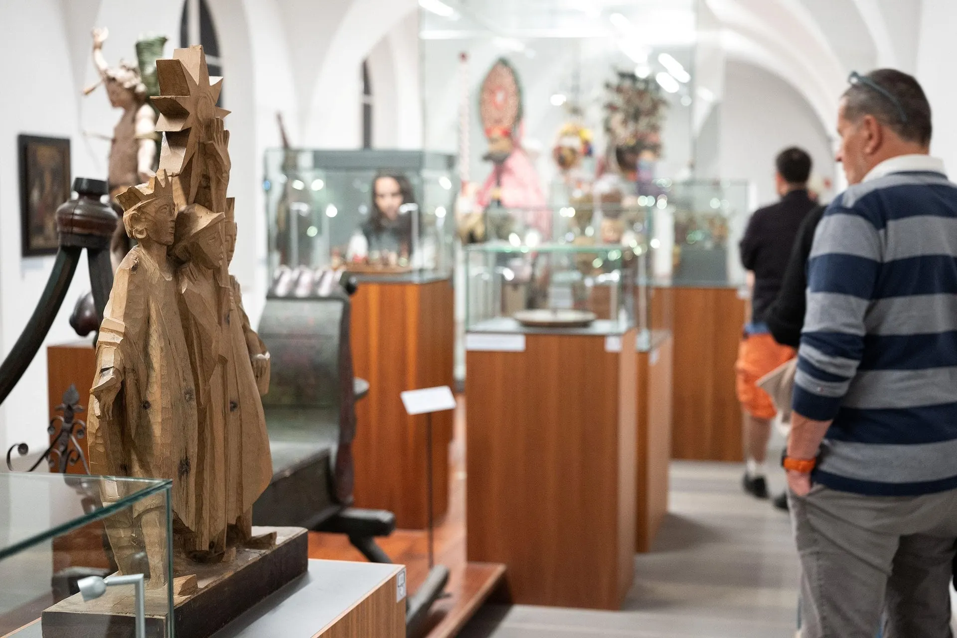 Visitors among carved figures and cases in the Tyrolean Folk Art Museum