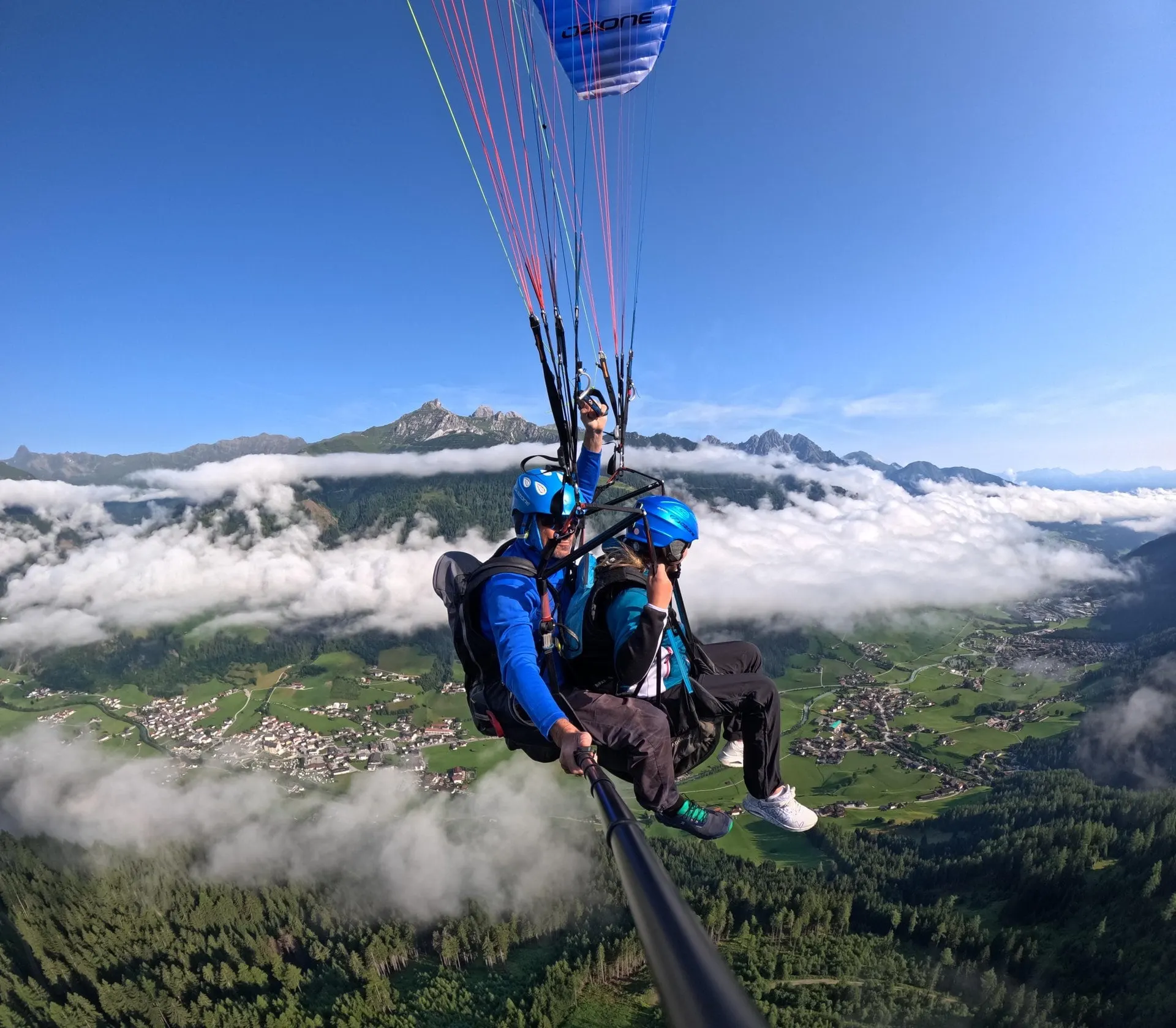 Tandem paragliders flying above clouds over the Stubai Valley