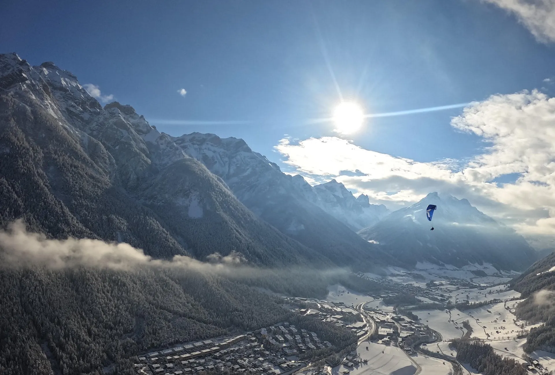 Paraglider above the Stubai Valley with mountain peaks and sun