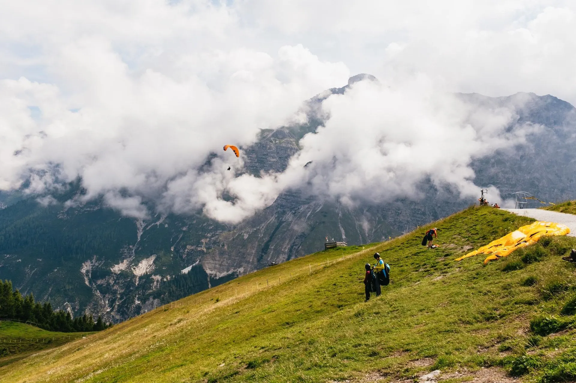 Paraglider launching from a grassy slope above the Stubai Valley