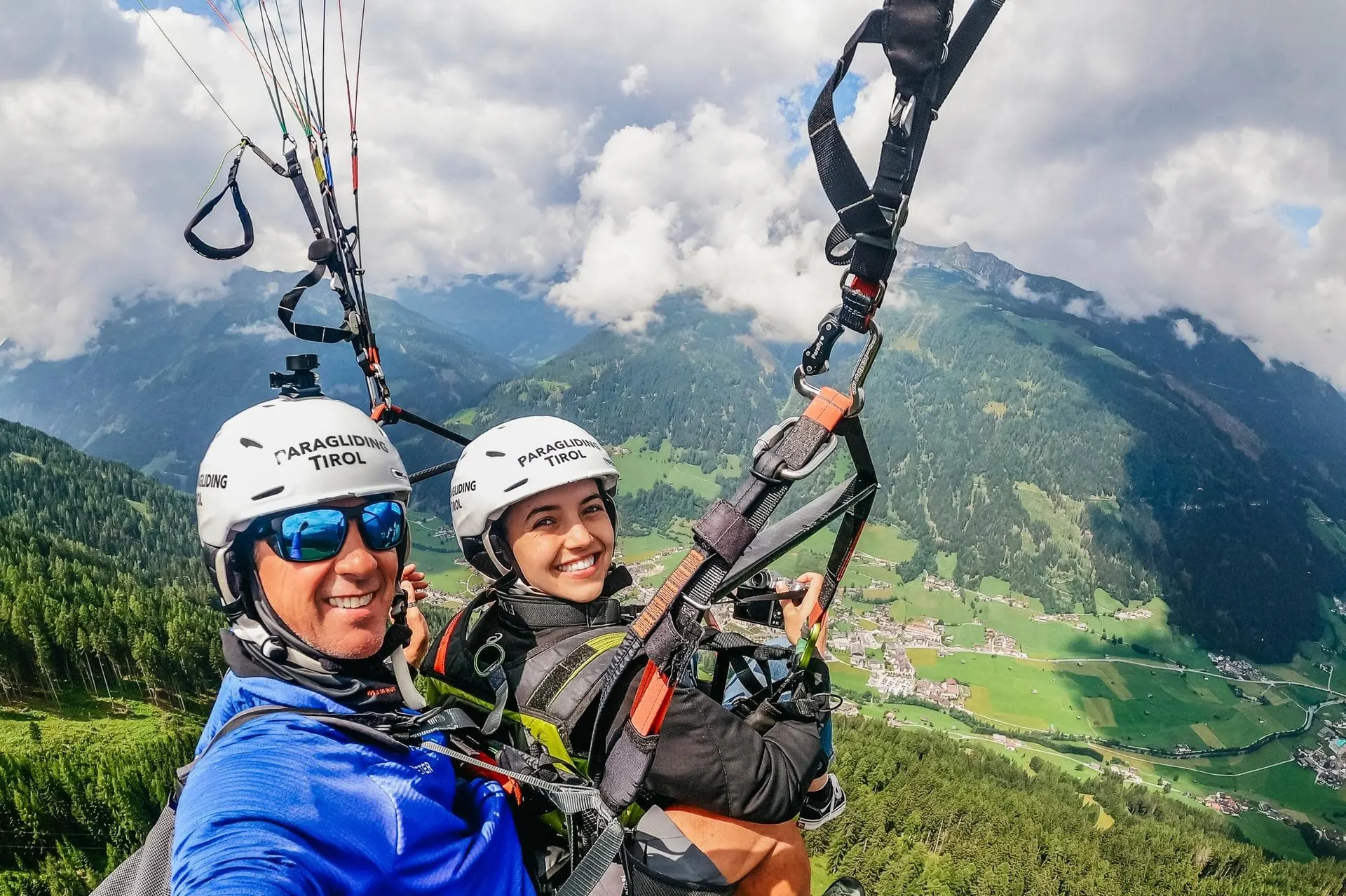 Tandem pilot and passenger smiling in flight above the Stubai Valley