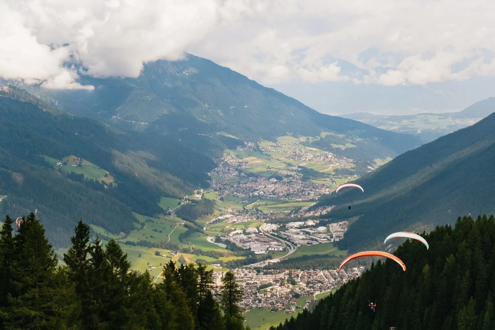 Paragliders flying over the Stubai Valley towards Neustift