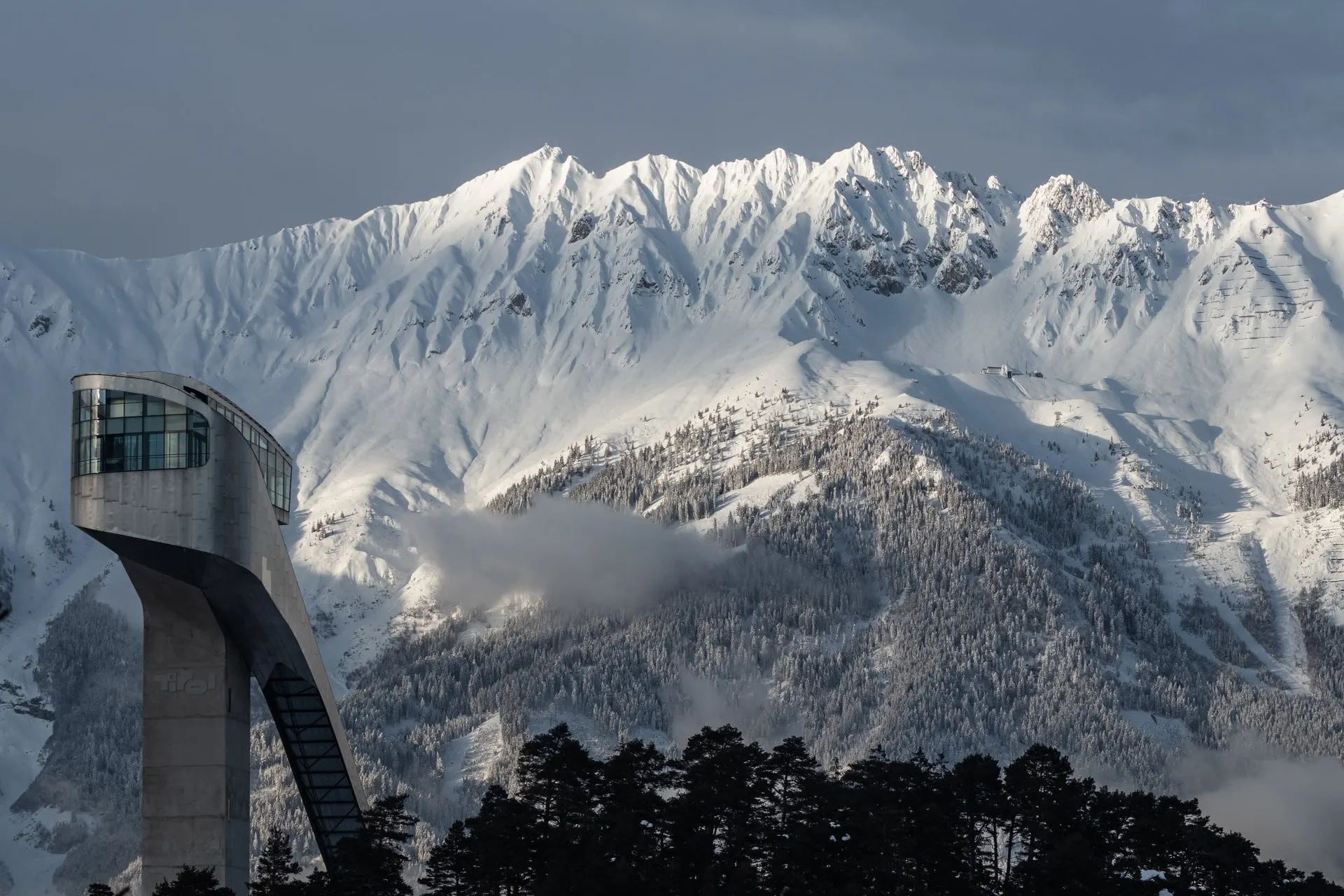 Bergisel ski jump tower in front of snowy peaks