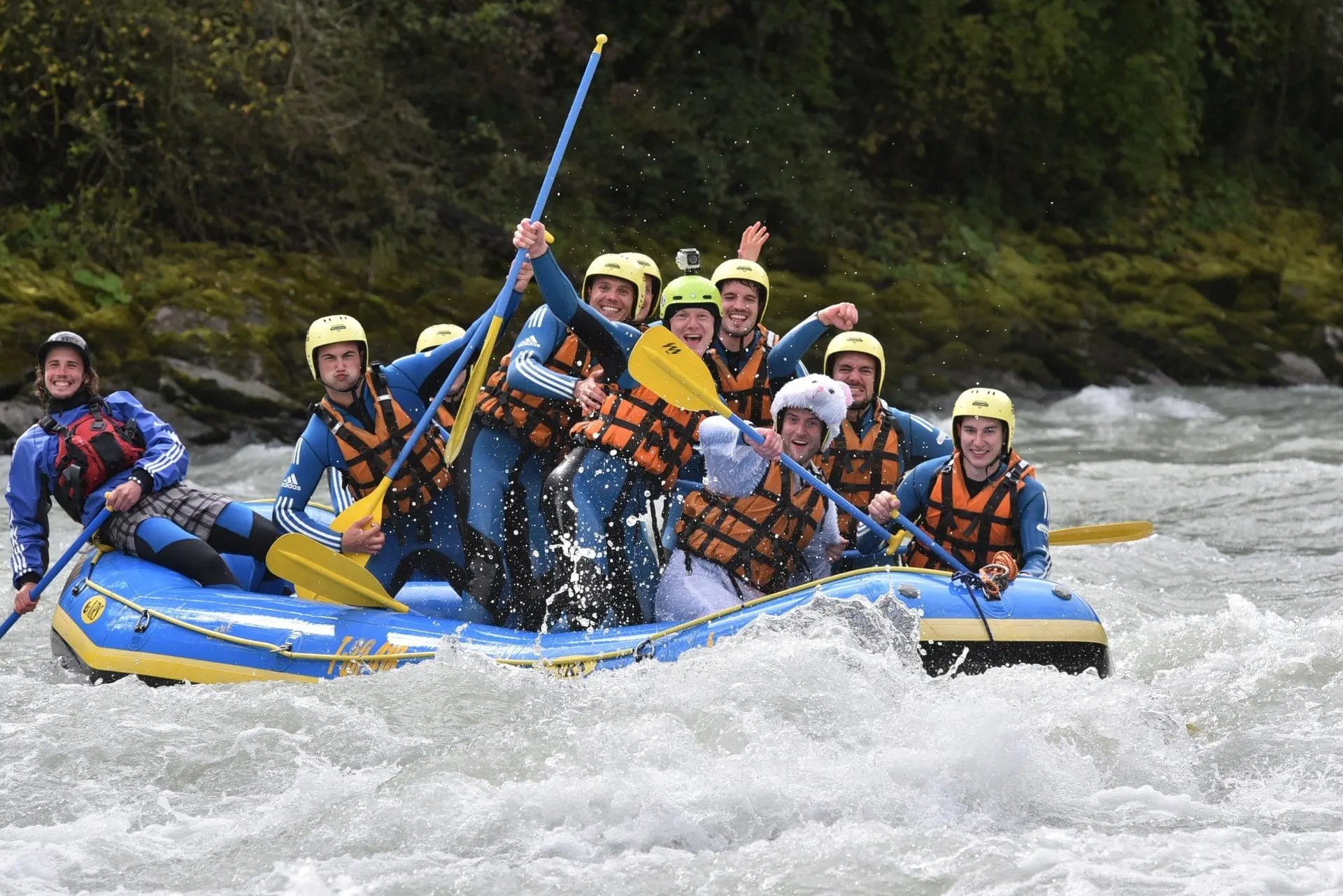 Cheering rafting group paddling through white water on the Inn