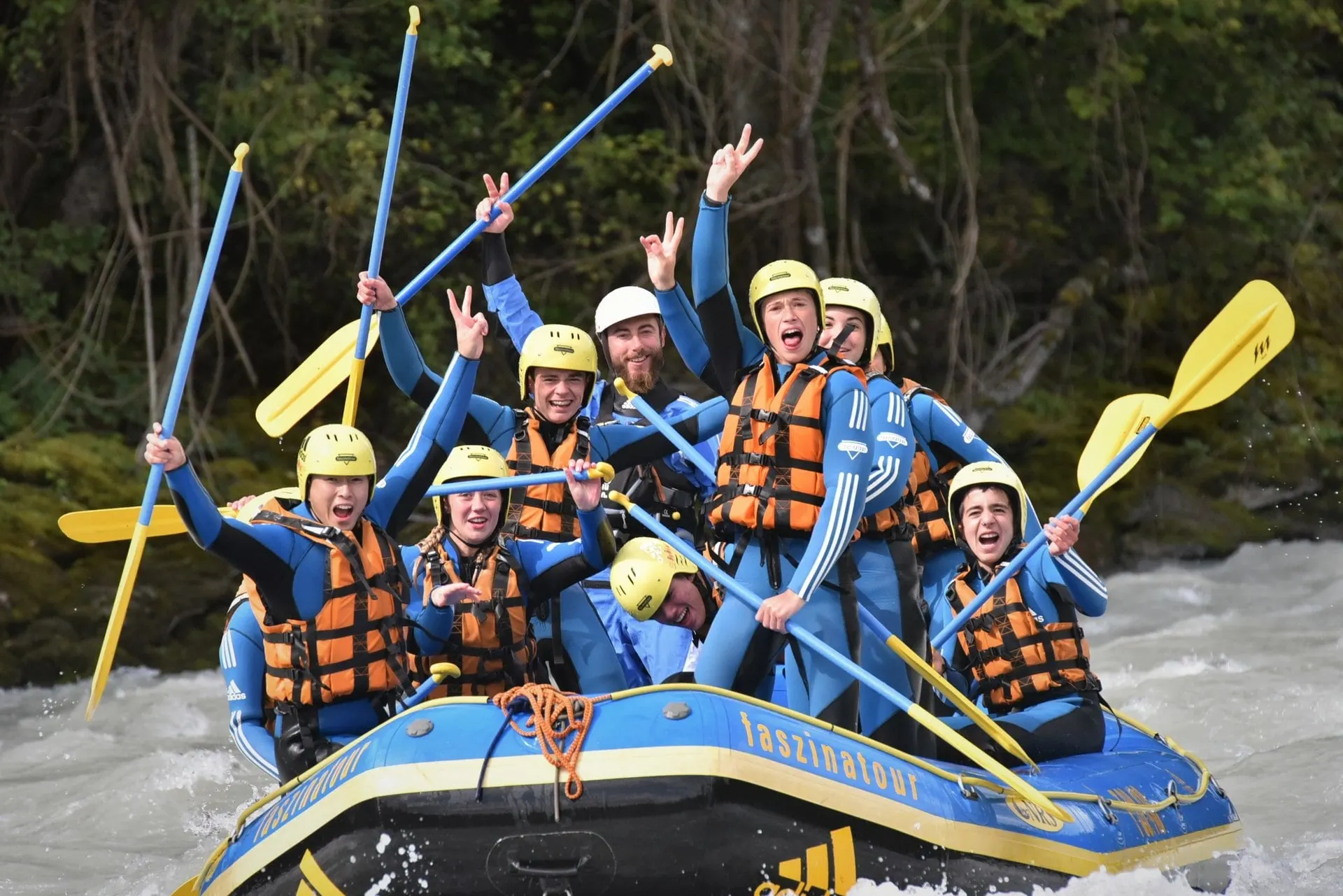Rafting team cheering with paddles raised on the Inn