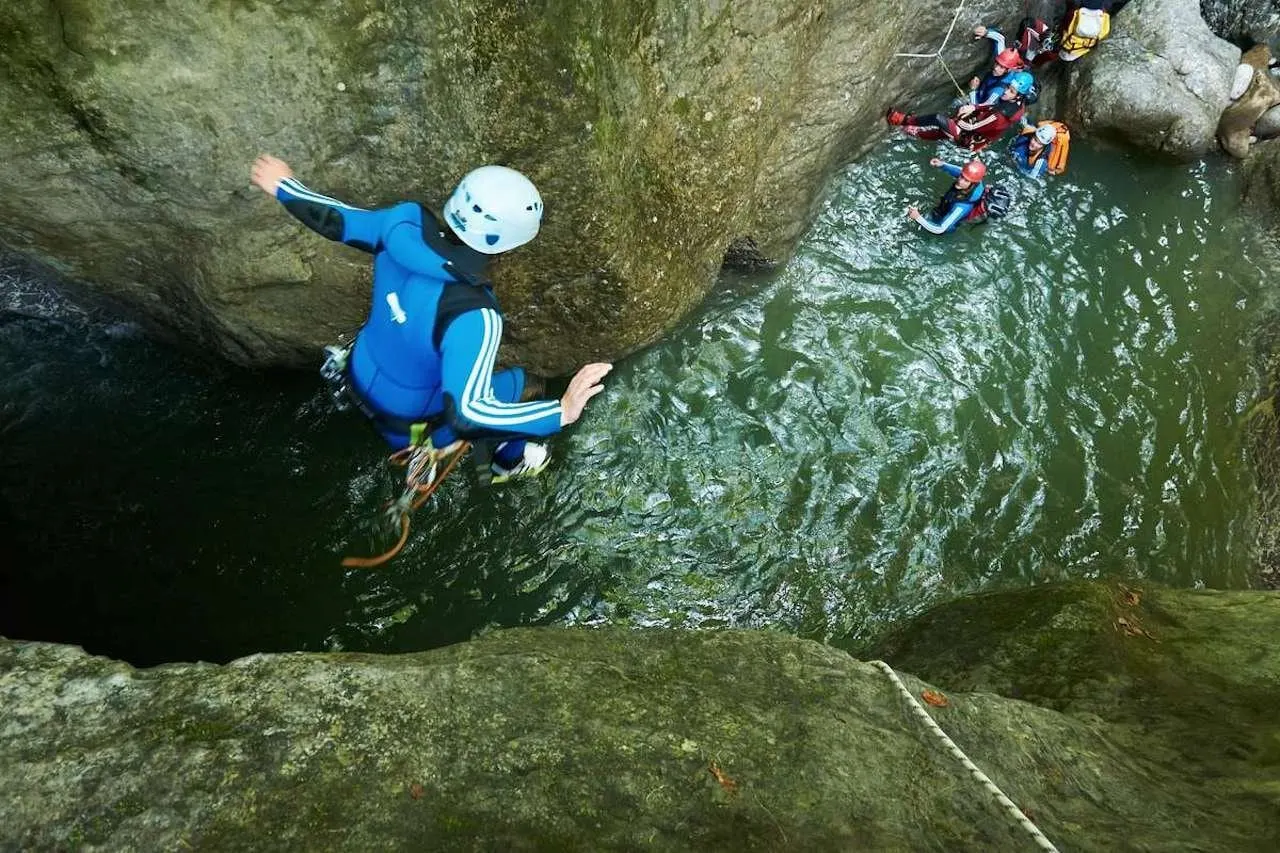 Canyoner jumping into a green pool in the gorge