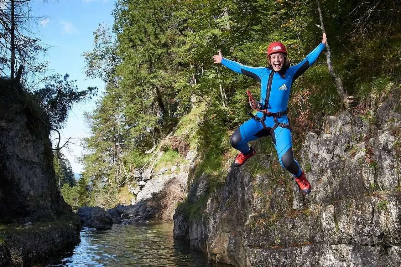 Canyoner leaping off a rock ledge into the gorge