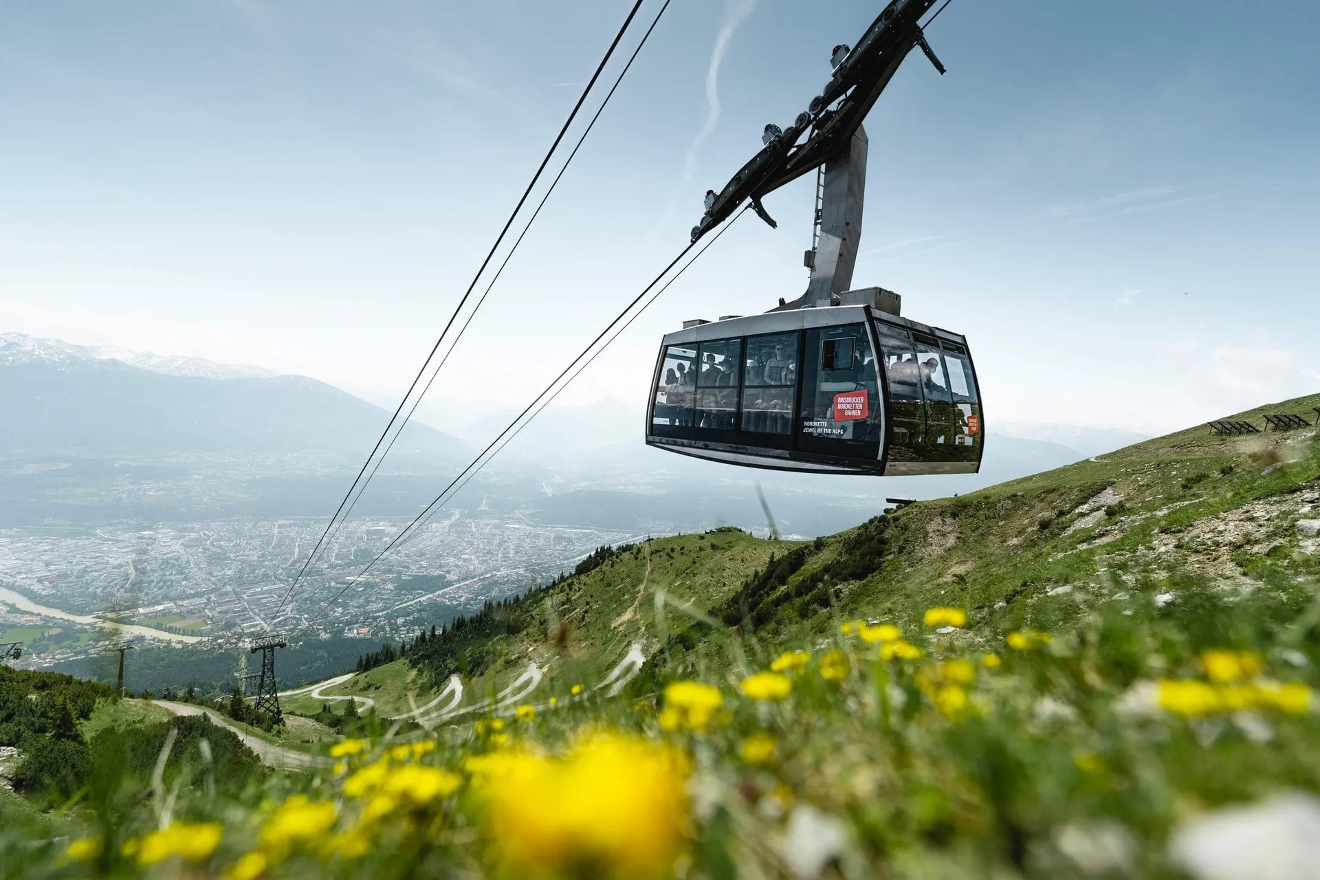 Nordkette gondola over wildflowers with Innsbruck below