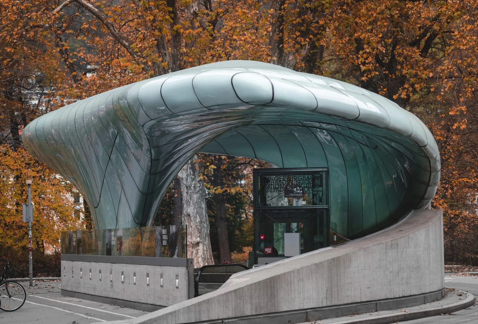 Glass roofed Hungerburg funicular station among autumn trees