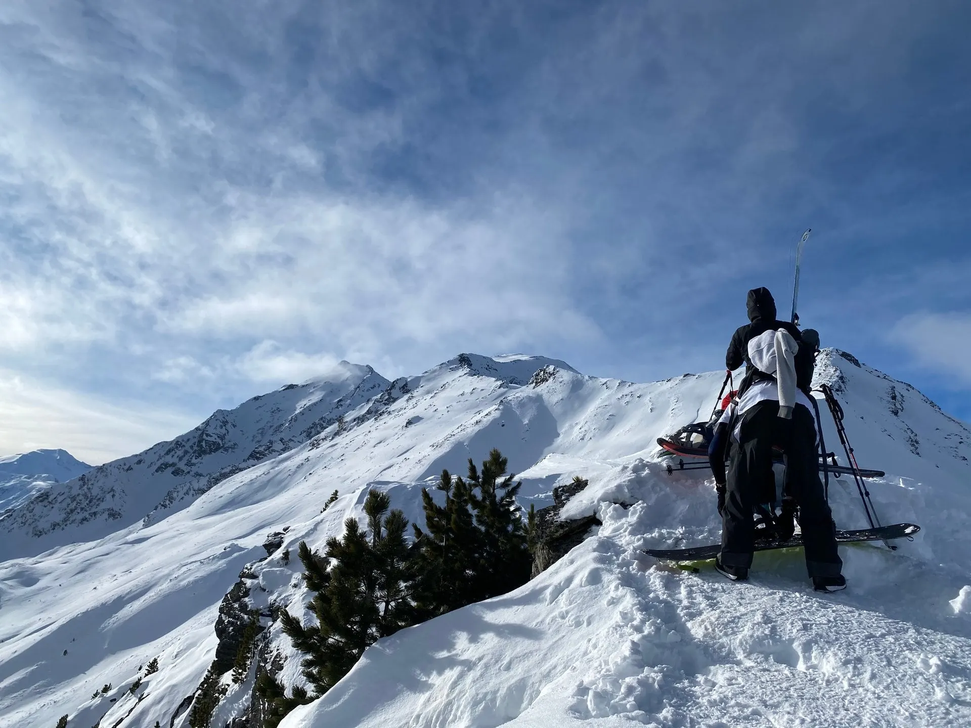Snowshoe hiker on a snowy ridge with peaks behind