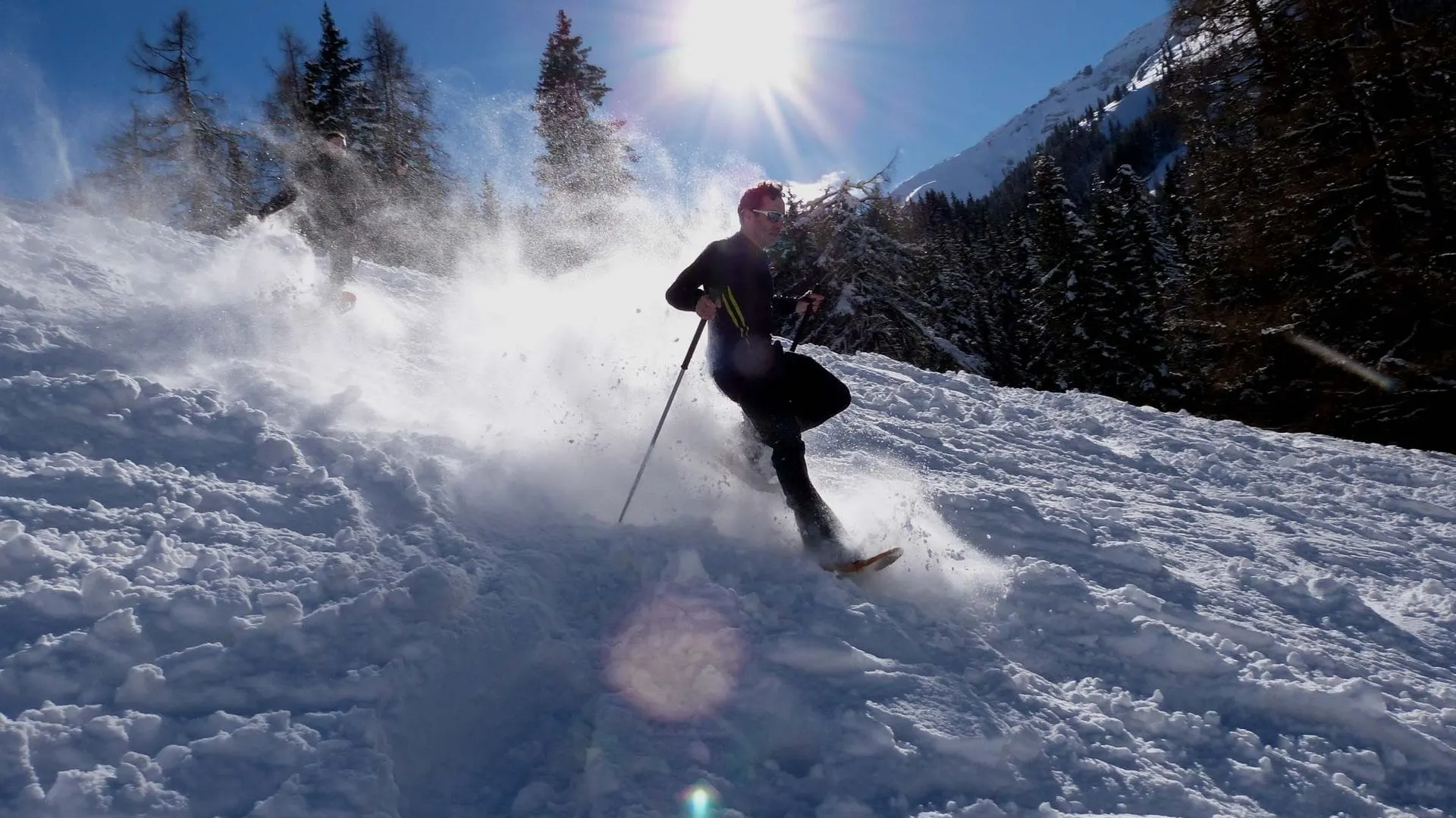 Snowshoer kicking up powder snow in the sunshine