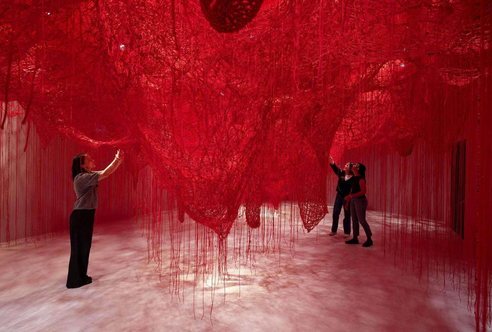 Visitors inside a red thread installation at Swarovski Crystal Worlds