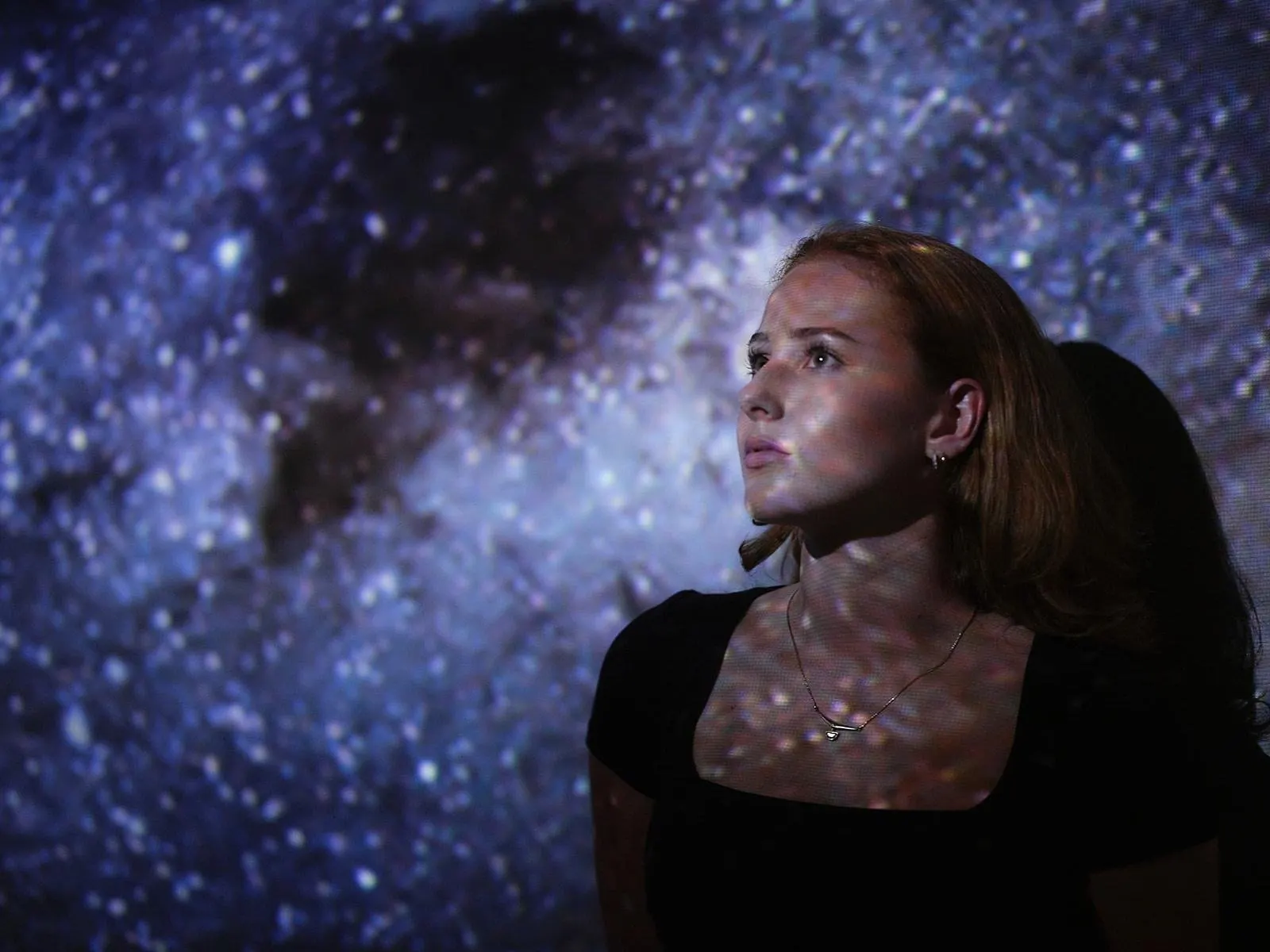 Visitor lit by a starry sky projection at Experience Tirol