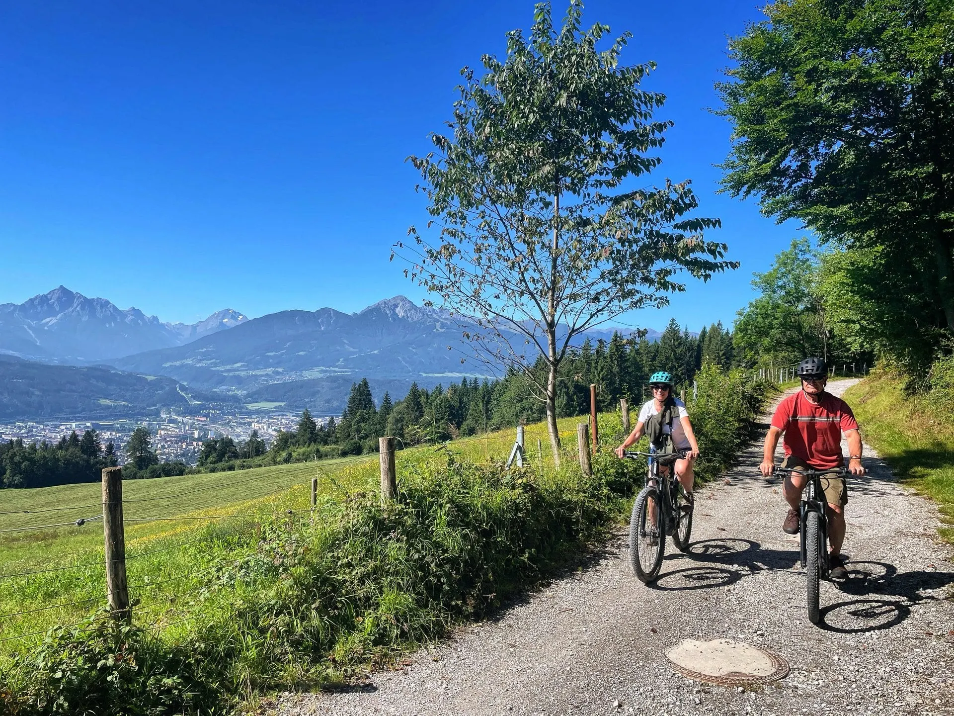 Electric bike riders on a gravel path above Innsbruck with mountains behind