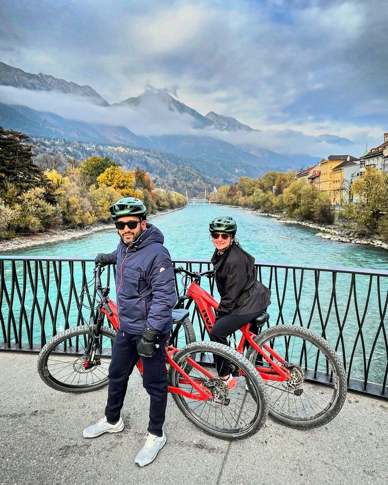 Couple with electric bikes on a bridge over the turquoise River Inn
