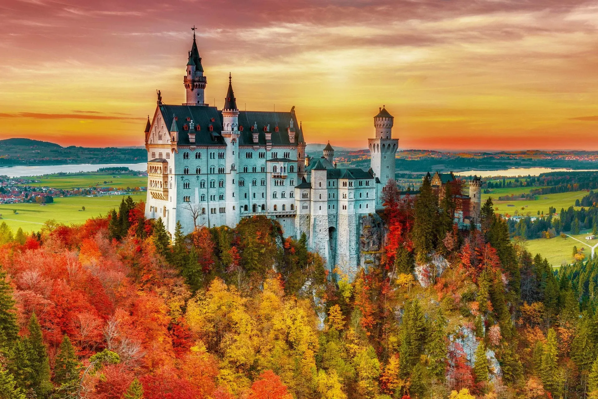 Schloss Neuschwanstein über herbstlichem Wald bei Sonnenuntergang