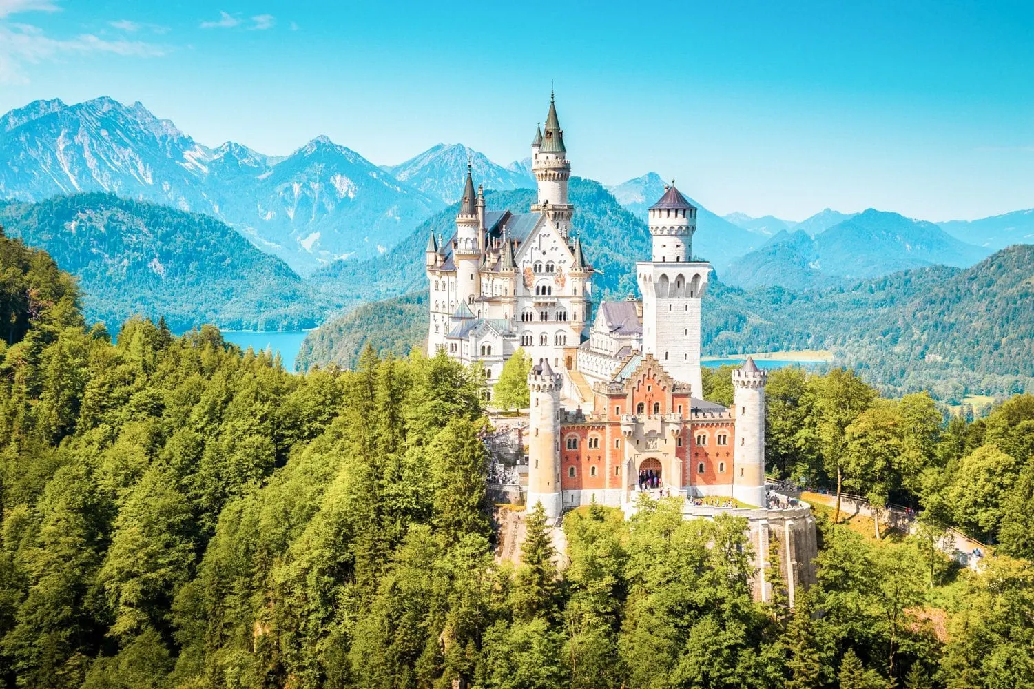Neuschwanstein Castle with turquoise lakes and the Alps behind